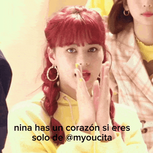 a girl with red hair is wearing a yellow hoodie and has a message in spanish