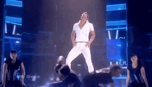 a man in a white shirt and white pants is dancing on a stage