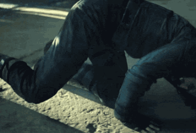 a man is crawling on the ground with his hands on his head