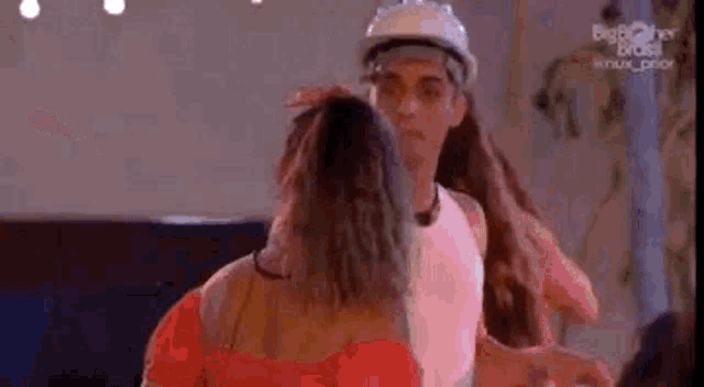 a man wearing a hard hat is standing next to a woman .