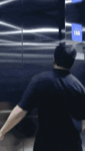 a man in a black shirt is standing in front of an elevator with the number 168 on it