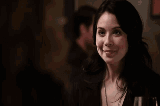 a woman is smiling and holding a glass of wine in her hand .