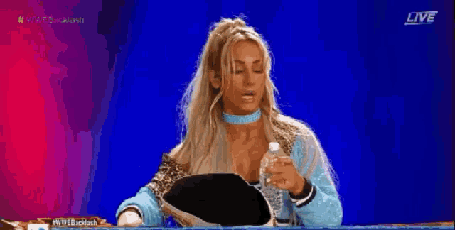 a woman is drinking water from a bottle on a blue background .