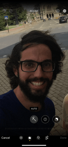 a man with glasses and a beard is smiling while adjusting his picture