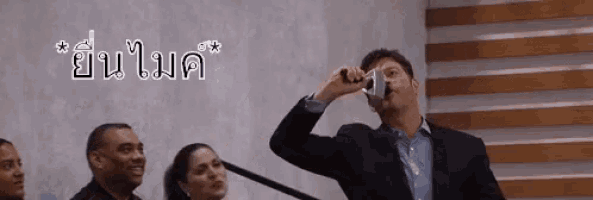 a man in a suit is taking a picture of himself with a camera in front of a microphone .