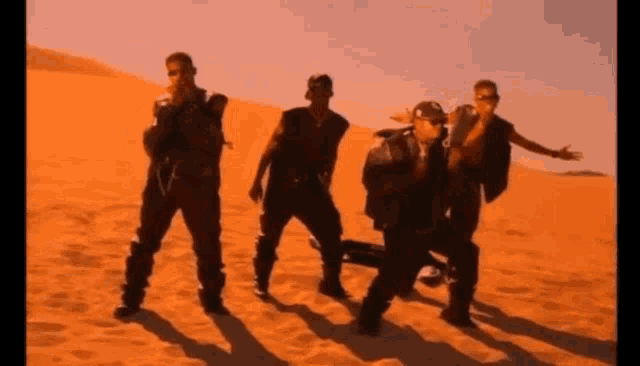a group of men are standing in the sand in a desert