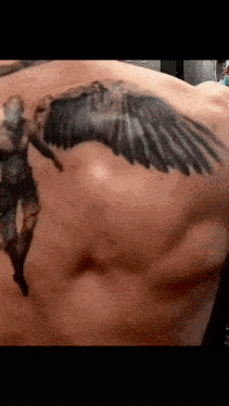 a close up of a man 's chest with a tattoo of wings on it .