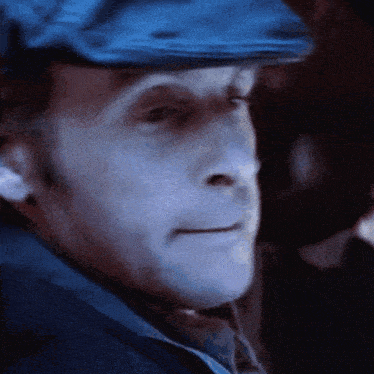 a close up of a man 's face wearing a blue hat and tie .