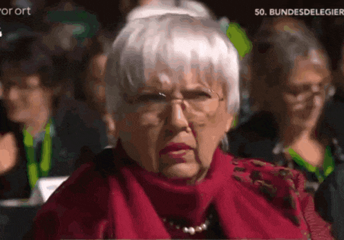 a woman with white hair and glasses is wearing a red scarf and a necklace