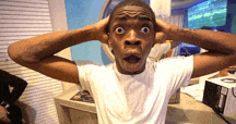 a man in a white shirt is making a surprised face with his hands on his head