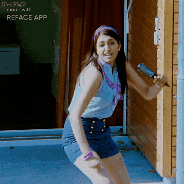 a woman in a blue shirt and blue shorts is dancing in front of a wooden building with reface app written on the bottom
