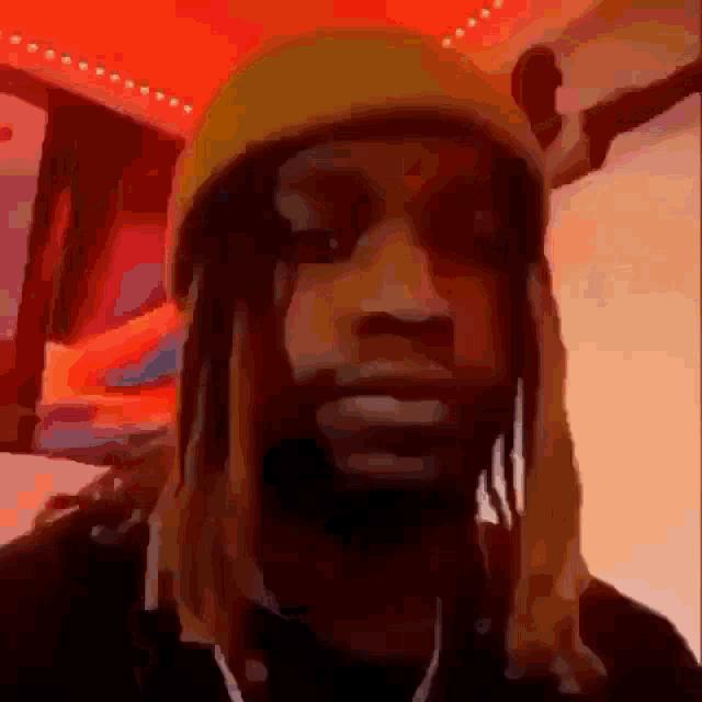 a man with dreadlocks is wearing a yellow hat and earphones .