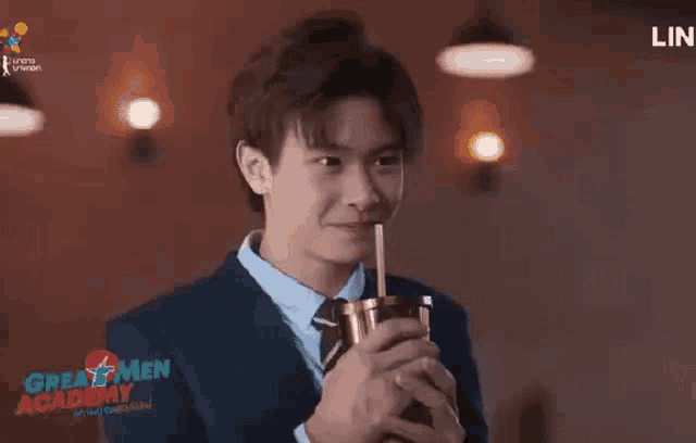 a man in a suit and tie is holding a cup with a straw and giving a thumbs up sign .