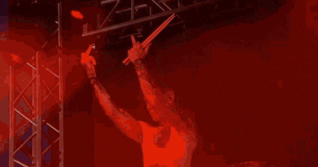 a shirtless man with tattoos on his arms is holding a drum stick