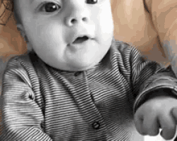 a baby wearing a striped shirt is looking at the camera