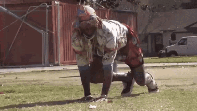 a man with dreadlocks is doing push ups in the grass .