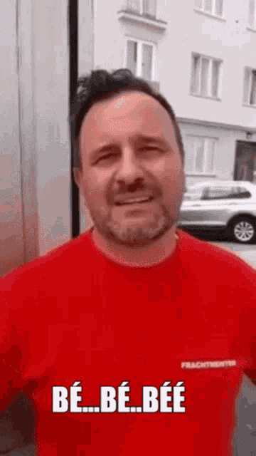 a man wearing a red shirt with the words be be bee on it