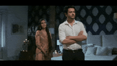 a man in a white shirt stands next to a woman in a bedroom