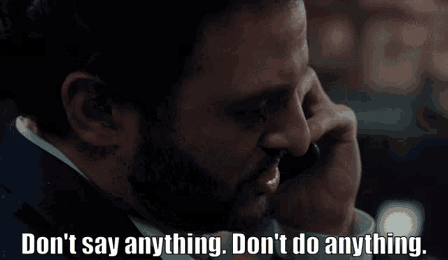 a man talking on a phone with the words " do n't say anything do n't do anything " written below him