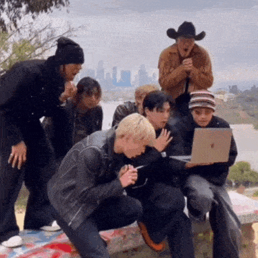 a man in a cowboy hat is looking at a laptop
