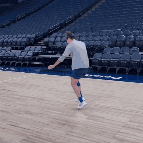 a person standing on a basketball court that has the word delaware on the floor