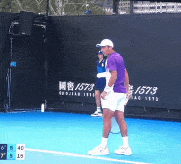 a man in a purple shirt is holding a tennis racquet on a blue tennis court