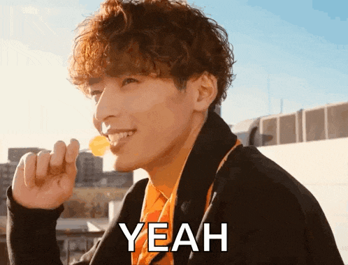 a man with curly hair is smiling while eating a potato chip and the word yeah is on the bottom