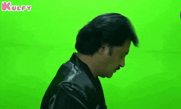 a man is standing in front of a green screen and making a funny face .