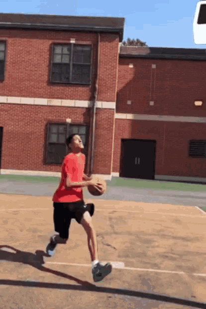 a man in a red shirt is holding a basketball on a court