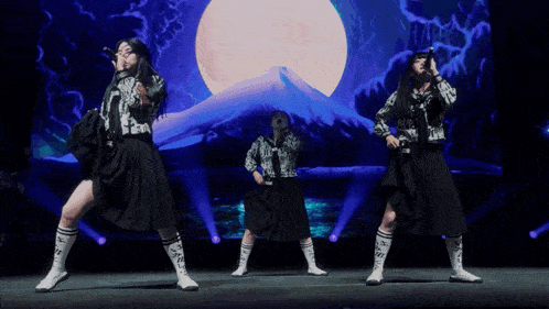 a group of girls are performing on a stage with a mountain in the background
