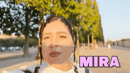 a woman taking a selfie in front of trees with the word mira above her