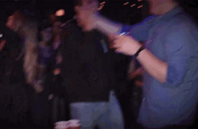 a man in a blue shirt is giving a high five to another man in a crowd