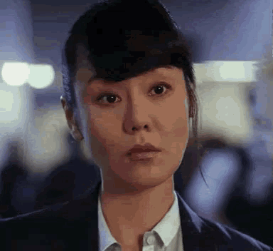 a close up of a woman 's face in a suit and white shirt .