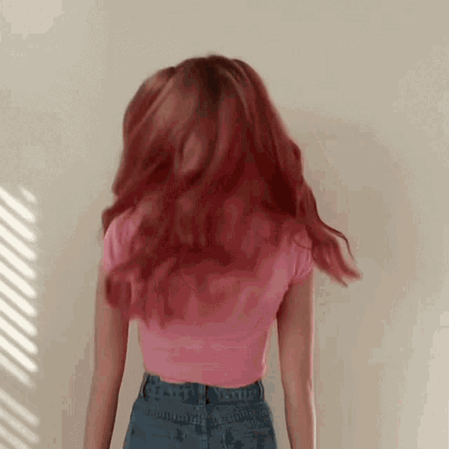 a woman with red hair is standing in front of a wall .