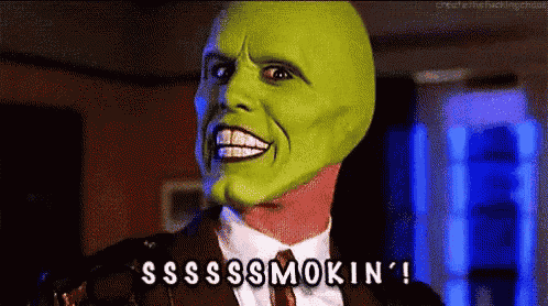 a man in a suit and tie with a green mask on his face is smoking .