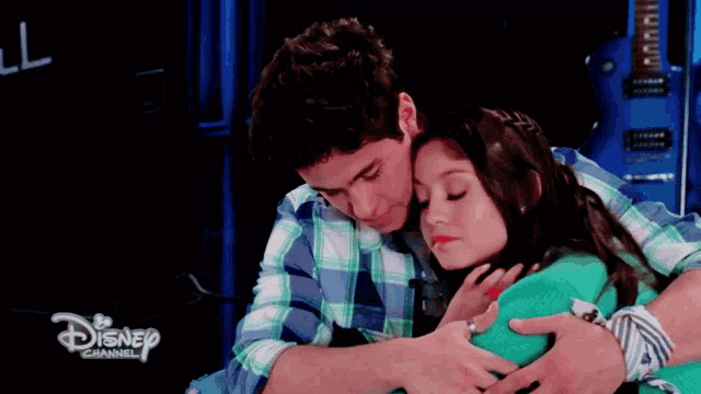 a boy and a girl hugging each other with a disney channel logo in the background
