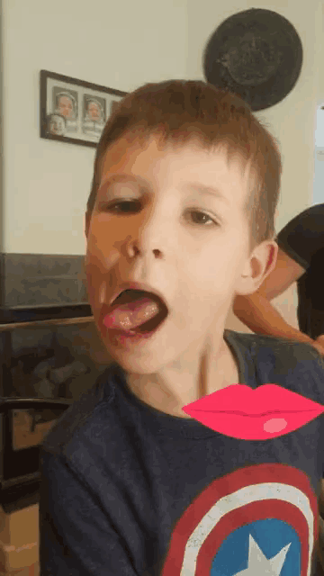 a young boy wearing a captain america shirt with his tongue out