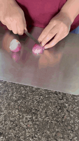 a person cutting an onion with a knife on a cutting board