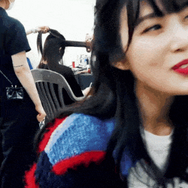 a woman with red lipstick is sitting in a chair with her hair curled
