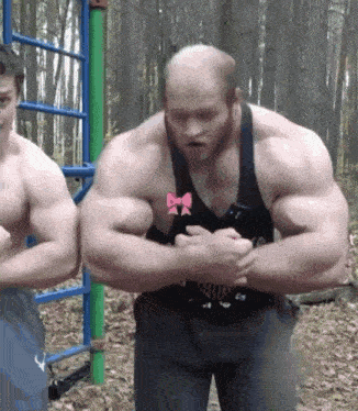 a man with a bow on his chest is flexing his muscles with another man