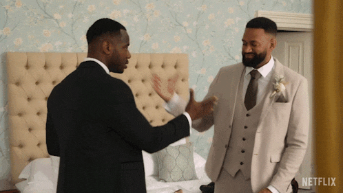 two men in suits standing next to each other in a room with a netflix logo in the corner