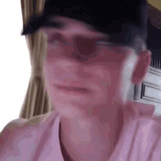 a man wearing a baseball cap and sunglasses is making a funny face .