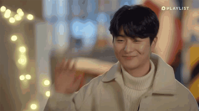 a man is smiling and waving his hand with a playlist logo in the corner