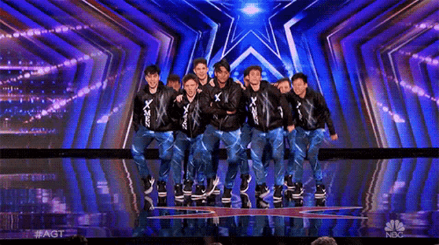 a group of boys are posing for a picture on a stage with a star in the background