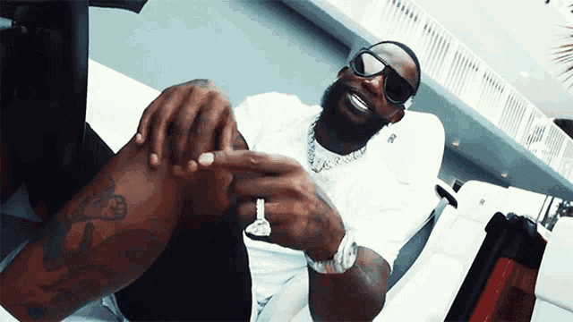 a man wearing sunglasses and a watch is sitting on a chair