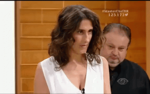 a woman in a white dress is standing next to a man in a black shirt on a tv show .