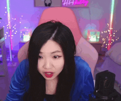 a woman in a blue jacket is sitting in a pink chair looking at the camera
