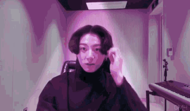 a man is sitting in a chair in a purple room with a piano in the background .