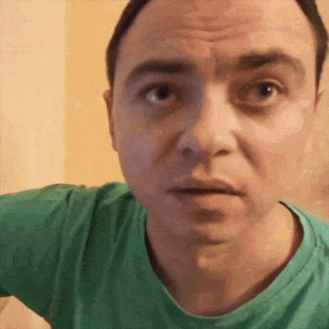 a man in a green shirt is looking at the camera