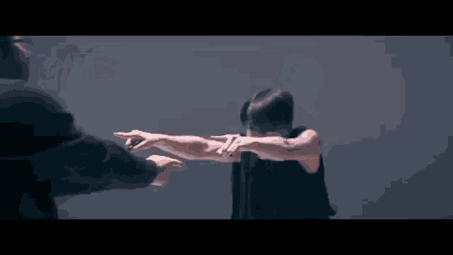 a man in a suit is pointing at a woman in a black dress with her arms outstretched .
